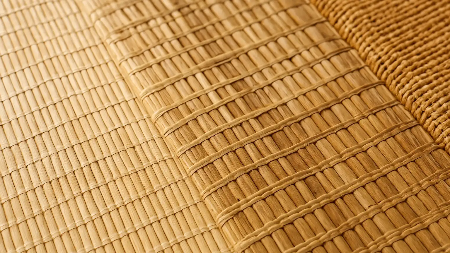 Close-up of three different woven bamboo shade samples laid flat, showing varied weave textures and natural color variations in natural light.
